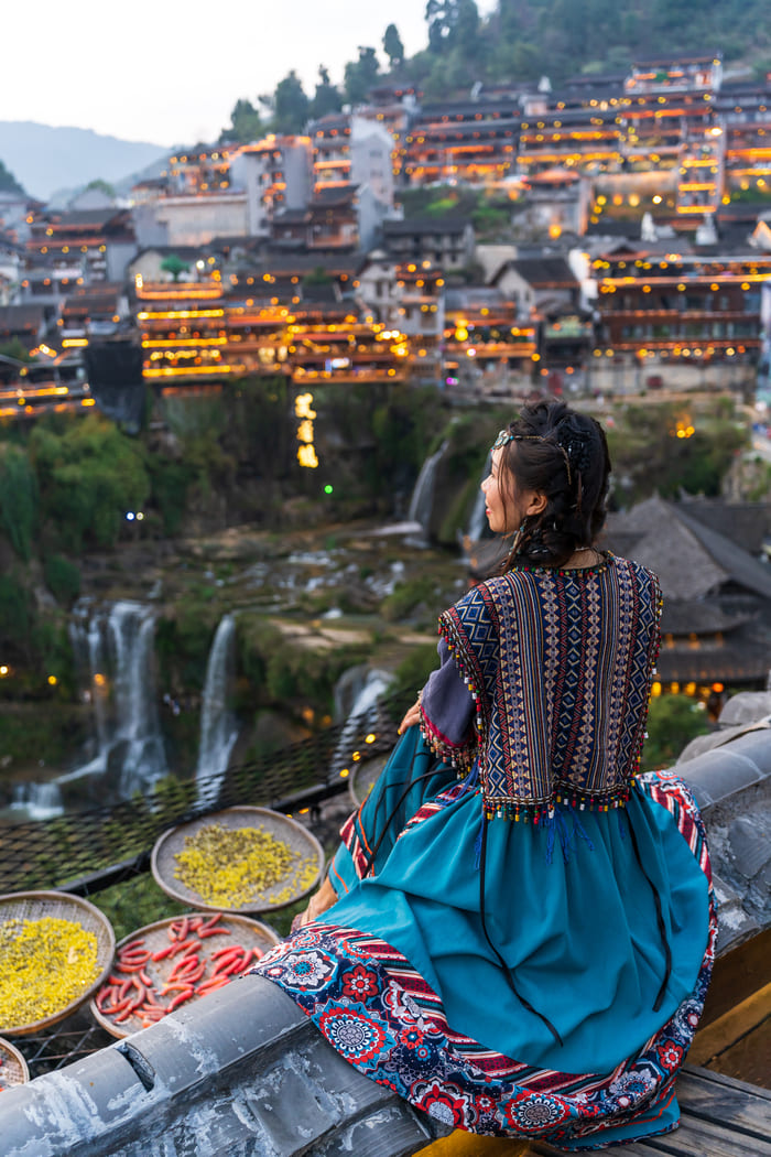 Mujer con ropa tradicional de campo viendo a la ciudad de Lijiang
